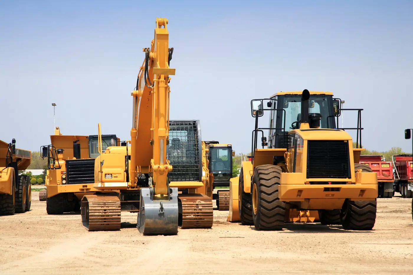 Excavators and loaders lined up at a construction yard