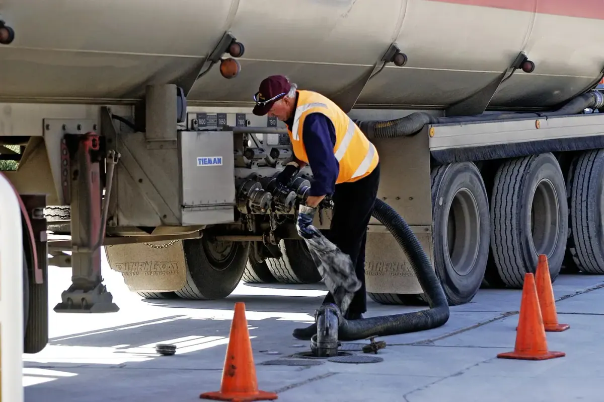 Driver wet-hose fueling a truck from a fuel tanker