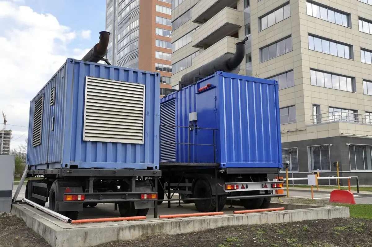 Containerized industrial diesel generators beside a building