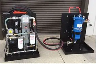 Two portable fuel polishing carts with pumps, spin-on filters, a canister filter housing and hoses, parked in front of a roll-up door