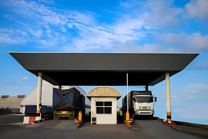 Trucks crossing a covered truck scale beside a scale house