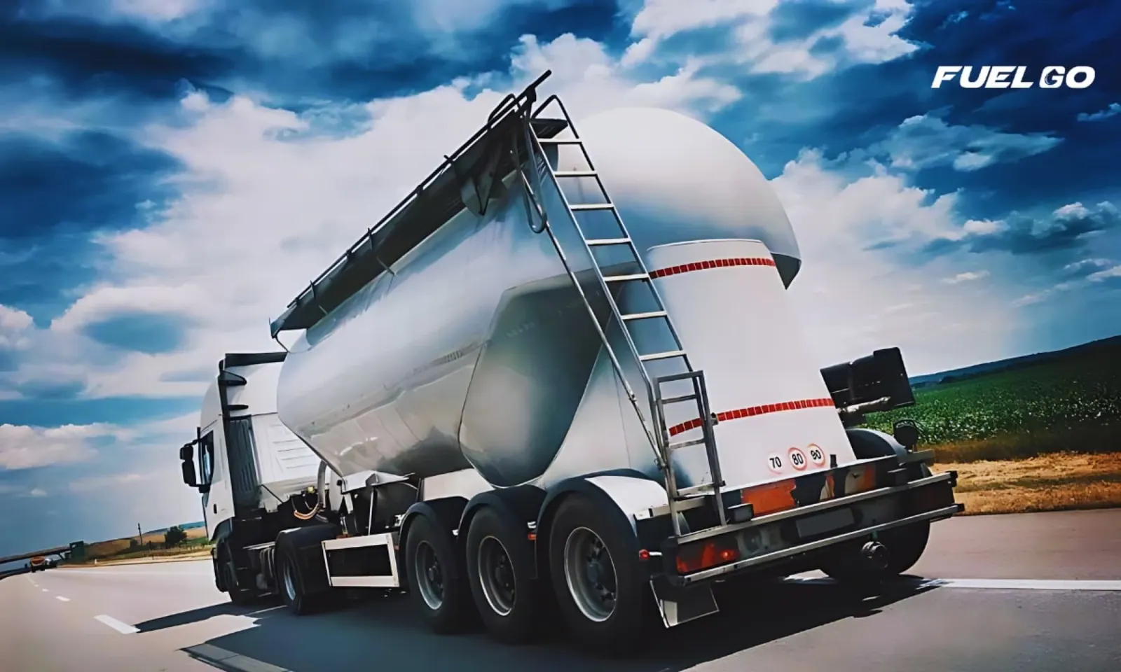 White semi truck pulling a silver dry-bulk tank trailer on a highway