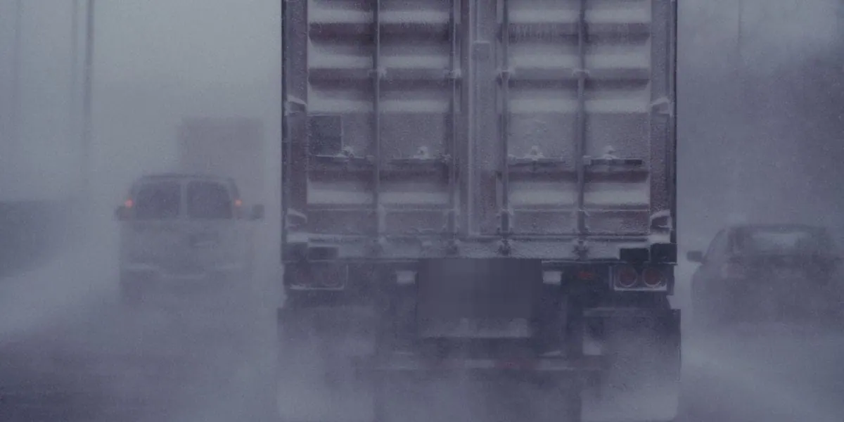 Semi truck trailer driving through a snowstorm on a Minnesota interstate