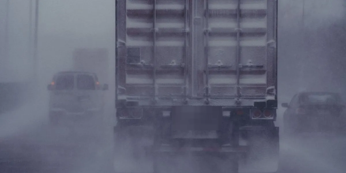 Semi truck trailer driving through a snowstorm on a Minnesota interstate